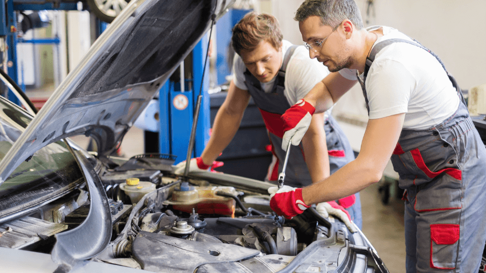 Mechanics working on car engine in garage