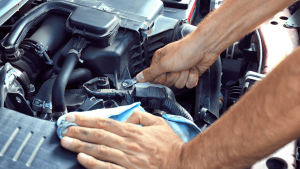 Hands fixing car engine with tools.