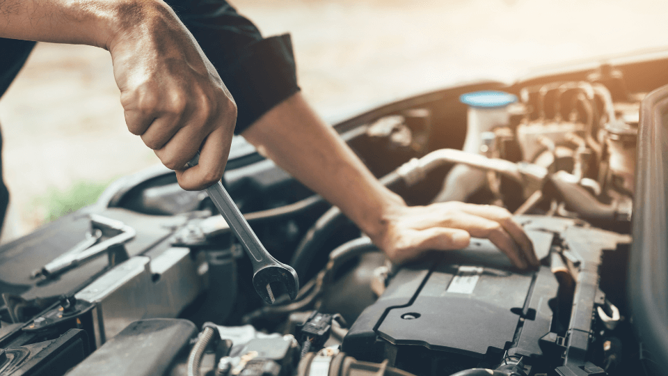 Mechanic working on car engine with wrench.